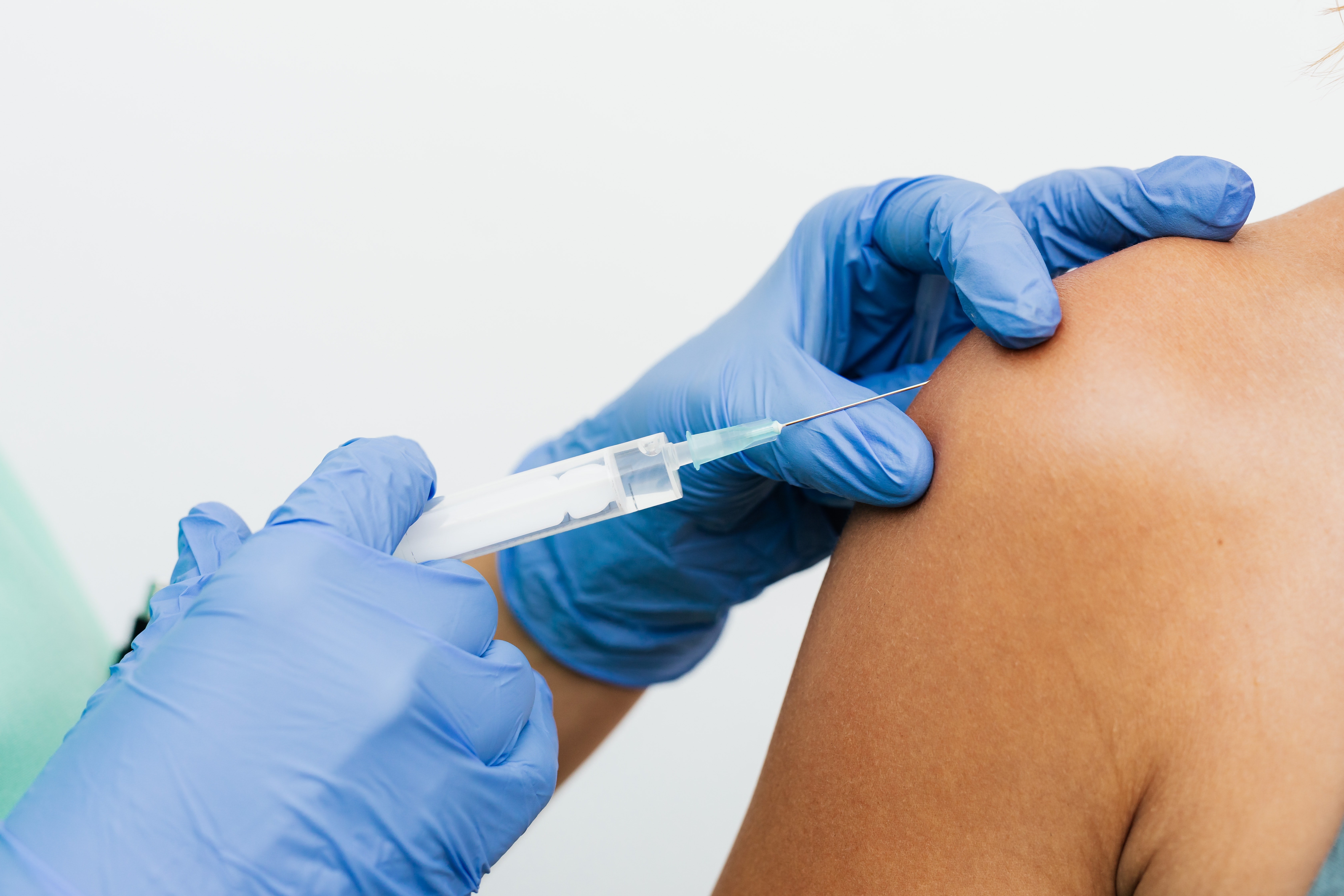Grafika przedstawiająca strzykawkę i ramię w trakcie szczepienia 